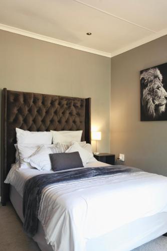 a bedroom with a large bed with a large headboard at Su Casa - Stylish & Spacious Guesthouse in Roodepoort