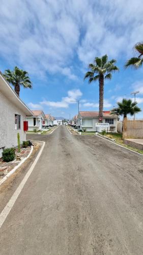 an empty street with palm trees and houses at Cabañas Pinamar in La Serena