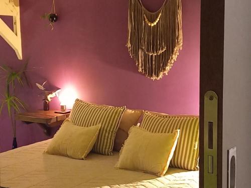 a bedroom with a bed with yellow pillows and a purple wall at Casa Bendita Pacha in Mar del Plata