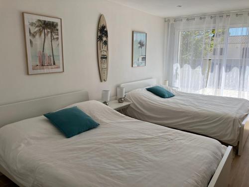 zwei Betten in einem Zimmer mit Fenster in der Unterkunft Maison 3 chambres Longeville in Longeville-sur-Mer