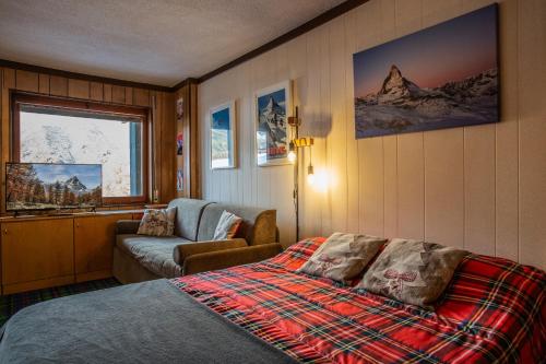 a bedroom with a bed and a couch and a window at Marcolski Home 2 in Breuil-Cervinia