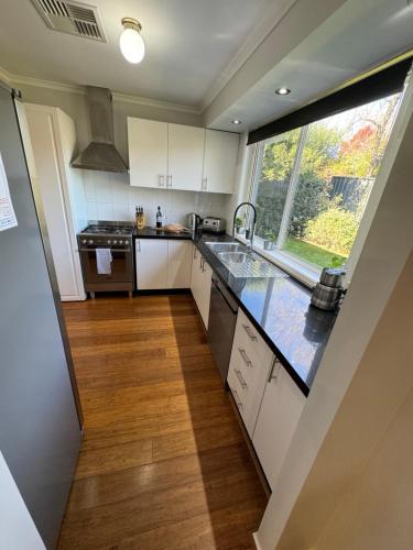 a kitchen with white cabinets and a large window at Belle in Bowral in Bowral