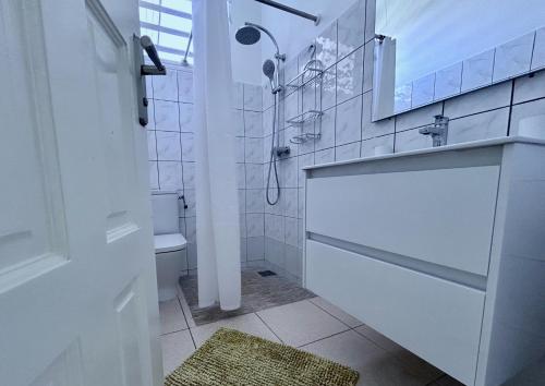 a white bathroom with a shower and a sink at Bleu Soleil in Le Morne-Vert