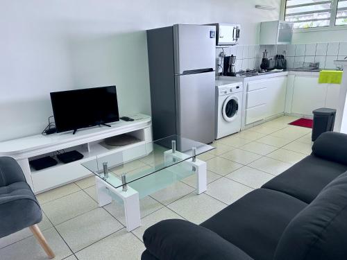 a living room with a couch and a tv and a kitchen at Bleu Soleil in Le Morne-Vert
