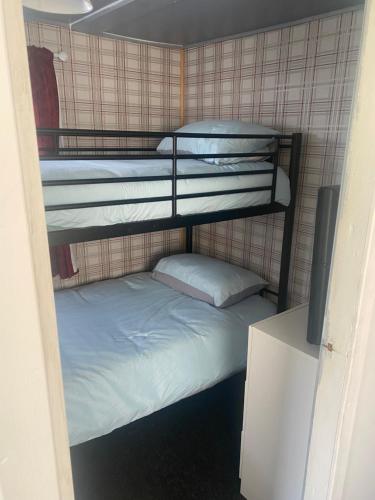 two bunk beds in a room with a bed at Beautiful Chalet close to the beach in Eastchurch