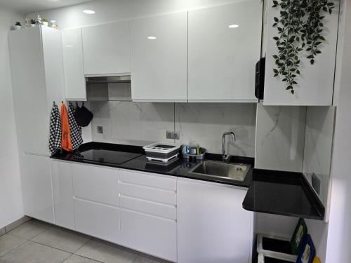 una cocina blanca con fregadero y armarios blancos en LC's Guesthouse, en Lagos