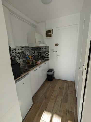 une cuisine avec des armoires blanches et un plancher en bois dans l'établissement Charmant studio calme et climatisé, près de la plage, à Canet en Roussillon, à Canet