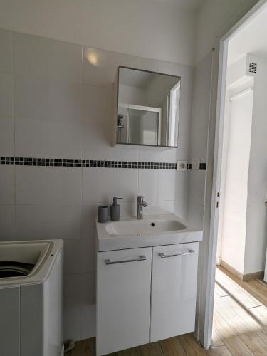une salle de bain blanche avec un lavabo et un miroir dans l'établissement Charmant studio calme et climatisé, près de la plage, à Canet en Roussillon, à Canet