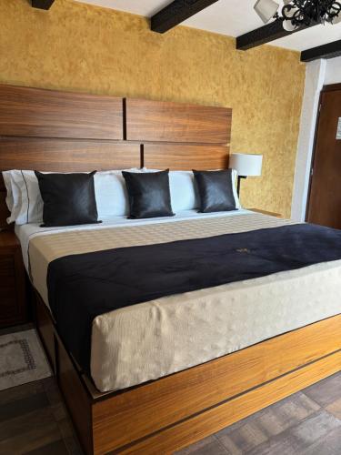 um quarto com uma cama grande e uma cabeceira em madeira em Hotel Boutique La Mansión Guadalajara em Guadalajara