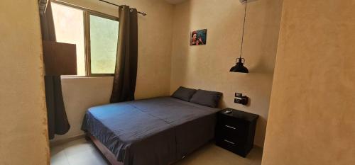 a small bedroom with a bed and a window at Departamentos MG in Valladolid