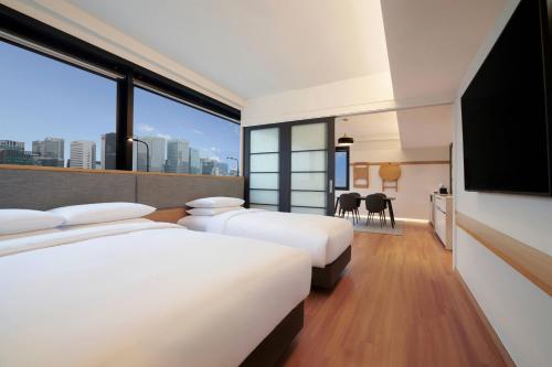 Habitación de hotel con 3 camas y TV de pantalla plana. en Moxy Seoul Insadong, en Seúl