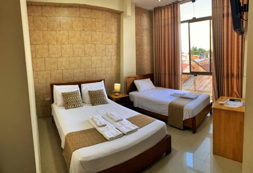 Habitación de hotel con 2 camas y ventana en Studio 69 Aparthotel en Iquitos