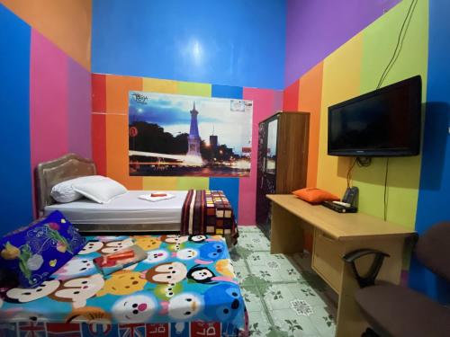 a colorful room with a bed and a television at Pelemkecut Double-Degree Syariah Accommodation in Kejayan
