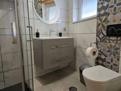 een badkamer met een toilet, een wastafel en een spiegel bij LC's Guesthouse in Lagos
