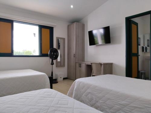 a hotel room with two beds and a flat screen tv at Colina del Sol Hotel Hacienda in Quimbaya