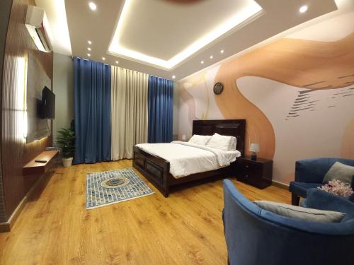 a bedroom with a bed and two blue chairs at Royal Lodge By Hotel Demanchi in Murree
