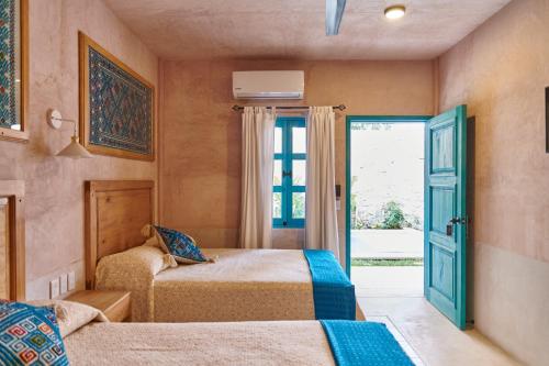 2 camas en una habitación con ventana y puerta en Hotel Mansión Chiapa, en Chiapa de Corzo