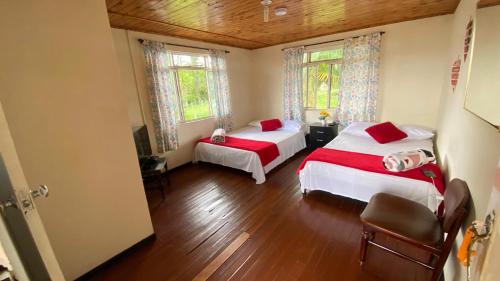a bedroom with two beds and two windows at Finca San Juan de las Araucarias Ranch in Santa Rosa de Cabal