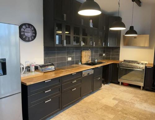 une cuisine avec des armoires noires et une horloge murale dans l'établissement Villa Johana, à Aucamville