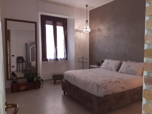 1 dormitorio con 1 cama grande y espejo en L'Archetto Apartment, en Civitavecchia