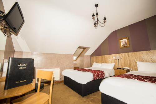 a hotel room with two beds and a flat screen tv at The Frontier Hotel in Bridgend
