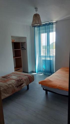 une chambre avec deux lits et une fenêtre avec des rideaux bleus dans l'établissement Appartement Kalysté, à Pietracorbara