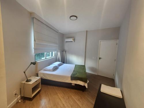 a bedroom with a bed and a desk and a window at Apartamento Modernizado in Rio de Janeiro