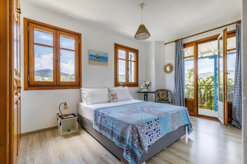ein Schlafzimmer mit einem Bett in einem Zimmer mit Fenstern in der Unterkunft Villa Daphne in Skopelos