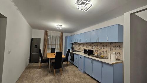 una cocina con armarios azules y una mesa con sillas en Casa de la Dunăre-Dăeni en Dăeni