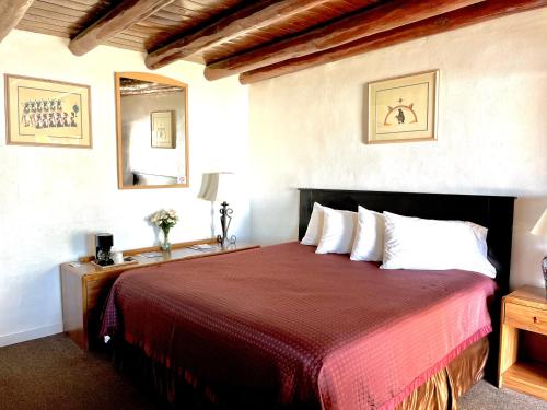 a bedroom with a large bed with a red blanket at Cottonwood Court Motel in Santa Fe