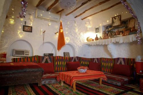 a living room with a red couch and a table at Thanmirth Ghardaia in El Ateuf