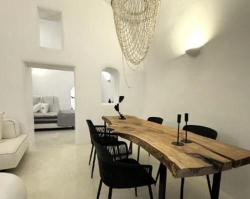 a dining room with a wooden table and chairs at Exquisite Santorini Villa Villa Kamelot 3 Bedrooms Spectacular Aegean Sea Views Private Outdoor Hot Tub Imerovigli in Imerovigli