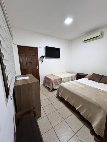 a hotel room with two beds and a flat screen tv at Acogedor independiente-Casa JH A in Santa Cruz de la Sierra