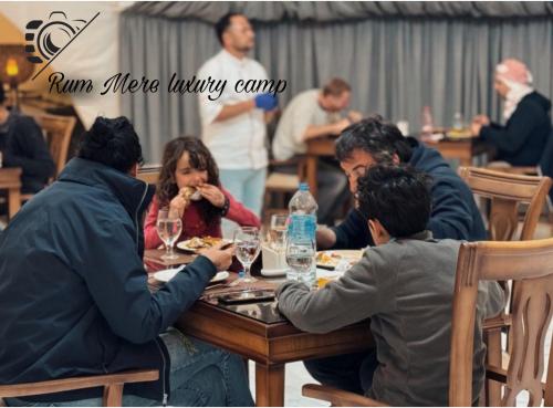 Eine Gruppe von Menschen, die an einem Tisch sitzen und Essen essen. in der Unterkunft Rum Mere luxury camp in Wadi Rum