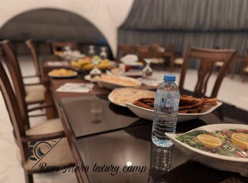 a table with plates of food and a bottle of water at Rum Mere luxury camp in Wadi Rum