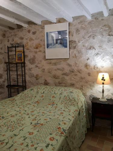 une chambre avec un lit et une table avec une lampe dans l'établissement Studio Tourrettes-sur-loup, le charme de l'ancien, à Tourrettes-sur-Loup