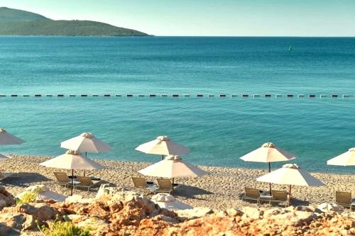 a group of umbrellas on a beach next to the water at LUSTICA BAY GARDEN APARTMENT, Centrale in Tivat