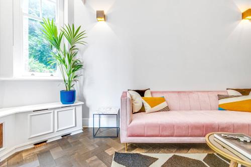 a living room with a pink couch and a potted plant at Flat in Chelsea in London