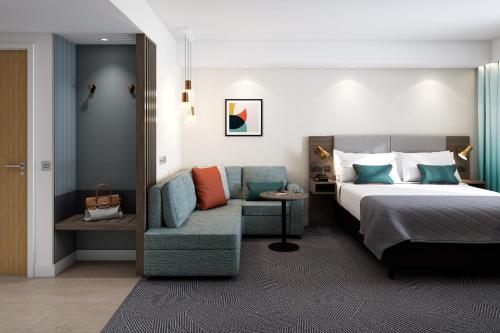 ディジョンにあるHoliday Inn Dijon Sud - Longvic, an IHG Hotelのベッドとソファ付きのホテルルーム
