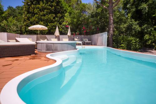 a blue swimming pool with chairs and an umbrella at Villaggio La Pescaccia in San Clemente