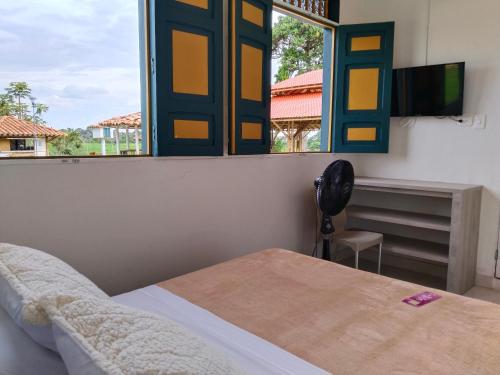 a bedroom with a window and a bed and a chair at Colina del Sol Hotel Hacienda in Quimbaya