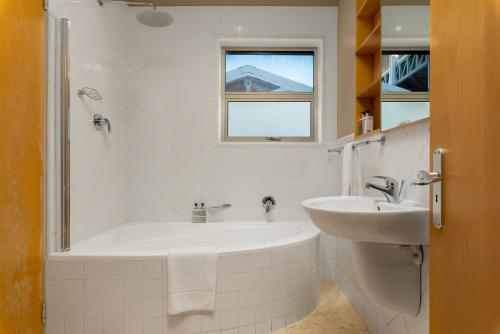 a white bathroom with a tub and a sink at Clifton Haven With Breathtaking Views in Cape Town