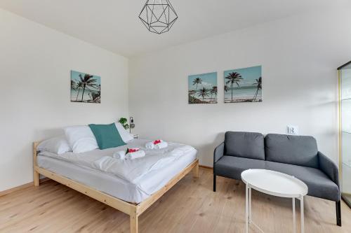 a bedroom with a bed and a couch and palm trees at Wave Apartments - Aurora in Gdynia
