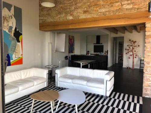 a living room with two white couches and a kitchen at appartement contemporain dans une authentique demeure viticole in Charnay-lès-Mâcon