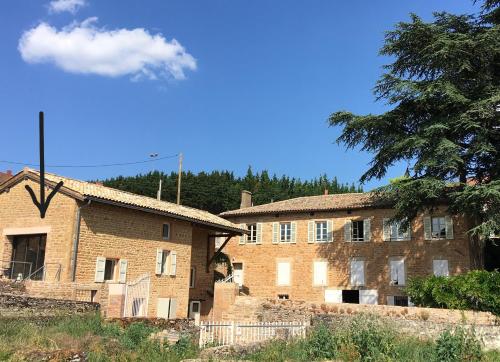 an old brick building with trees in the background at appartement contemporain dans une authentique demeure viticole in Charnay-lès-Mâcon