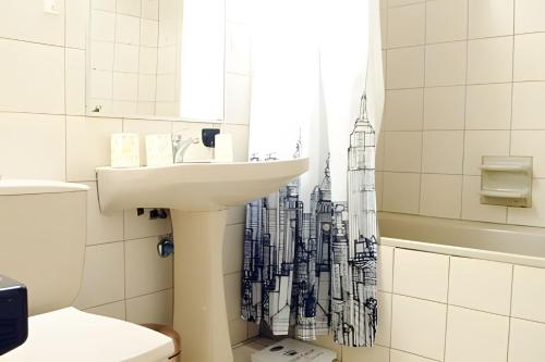 baño con lavabo y cortina de ducha en Living Paris en Santiago