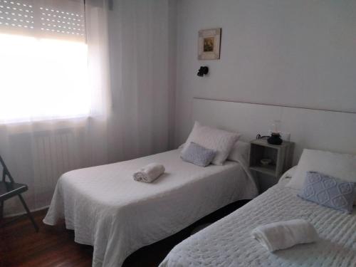 Ce lit se trouve dans un dortoir doté de murs blancs et d'une fenêtre. dans l'établissement HR Liberdade, à Sarria