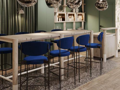 - un bar avec des chaises bleues dans une pièce aux murs verts dans l'établissement Mercure Annecy Centre, à Annecy