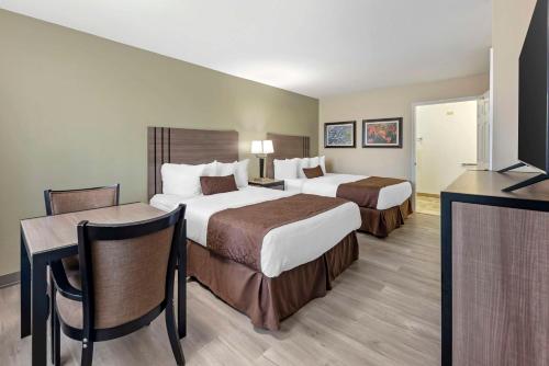 a hotel room with two beds and a desk at Best Western Inn of Brenham in Brenham