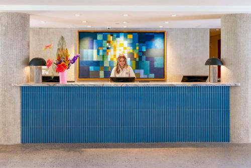 a woman on a tv screen behind a blue counter at Wayfinder Waikiki in Honolulu